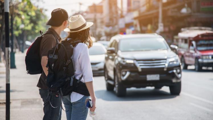 Tourists at the side of the road waiting for a car